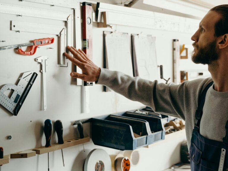 Carpenter with gray long sleeves organizing hand tools in a workshop, enhancing efficiency.